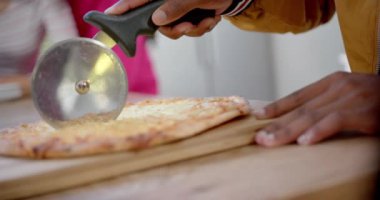 Çeşitli genç arkadaşlar mutfakta pizza pişirir ve keserler, ağır çekimde. Gen z, arkadaşlık, takılma, yemek ve yaşam tarzı, değişmemiş.