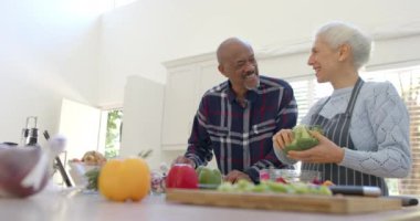 Mutfakta tablet, kopyalama alanı ve ağır çekim kullanarak sebze hazırlayan mutlu yaşlı çift. İletişim, ev hayatı, yemek pişirme, emeklilik ve sağlıklı yaşam tarzı, değişmedi..