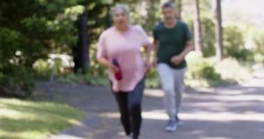 Güneşli havada koşan ve su şişesi tutan mutlu son sınıf çifti. Emeklilik, boş zaman, sağlıklı yaşam tarzı, birliktelik ve doğa konsepti, değişmemiş..