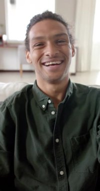 Çift ırklı bir adamın evde konuştuğu ve video görüşmesi yaptığı dikey video, yavaş çekim. Ev hayatı, teknoloji ve yaşam tarzı, değişmedi..