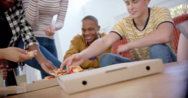 Kanepede oturan ve evde pizza yiyen çeşitli genç arkadaşlar grubunuz kutlu olsun. Gen z, arkadaşlık, takılma, yemek ve yaşam tarzı, değişmemiş.