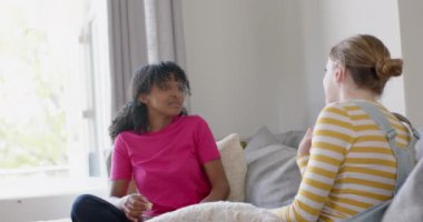 Mutlu genç bayan arkadaşlar evdeki kanepede oturup patlamış mısır yiyor, yavaş çekimde. Aile hayatı, dostluk, yemek ve yaşam tarzı, değişmemiş..