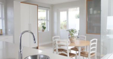 Büyük, beyaz, bitkilerle dolu bir mutfak, büyük bir gardırop ve sandalyeli bir masa, yavaş çekim. Tasarım, yemek pişirme ve mimari.