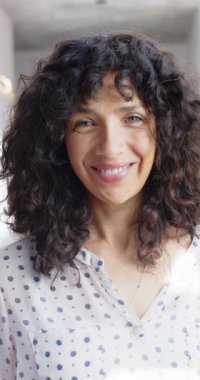 Evde kıvırcık saçlı, mutlu, melez bir kadının portresinin dikey videosu, yavaş çekim. Ev hayatı ve yaşam tarzı değişmedi..