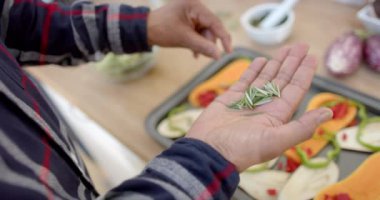Kıdemli Afro-Amerikan erkek aşçılığının orta kesimi, mutfakta baharatlı sebzeler, yavaş çekim. Ev hayatı, yemek pişirme, emeklilik ve sağlıklı yaşam tarzı..