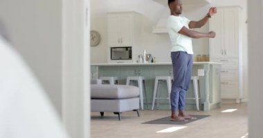 Odaklanmış Afro-Amerikan adam güneşli oturma odasında geriniyor, ağır çekimde. Ev, egzersiz, fitness ve sağlıklı yaşam tarzı, değişmemiş..