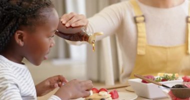 Mutlu Afro-Amerikan anne ve kızı evde krep yiyor, ağır çekimde. Aile hayatı, yemek, aile ve yaşam tarzı, değiştirilmemiş..