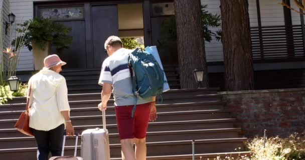 Boldog Változatos Idős Pár Akik Bőröndökkel Sétálnak Egy Napfényes Házig — Stock videók