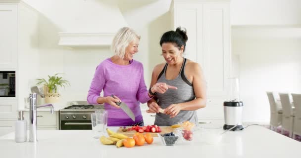 Duas Mulheres Idosas Diversas Felizes Cortando Frutas Rindo Cozinha Ensolarada — Vídeo de Stock