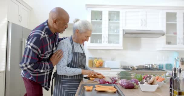 Ευτυχισμένο Ηλικιωμένο Ζευγάρι Που Προετοιμάζει Λαχανικά Και Αγκαλιάζει Στην Κουζίνα — Αρχείο Βίντεο