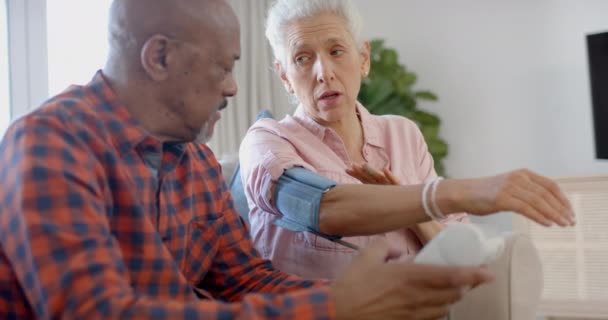 Poważna Para Seniorów Siedząca Kanapie Sprawdzająca Ciśnienie Krwi Domu Zwolniona — Wideo stockowe