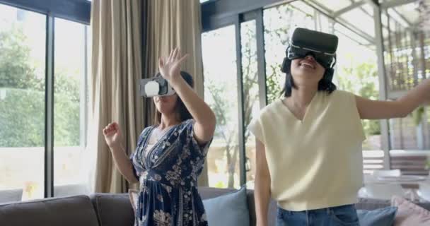 ハッピーアジアの女性の友人は 日当たりの良いリビングルームでガラスとダンスを使用して スローモーション ライフスタイル フリータイム 家庭生活 コミュニケーション テクノロジー — ストック動画
