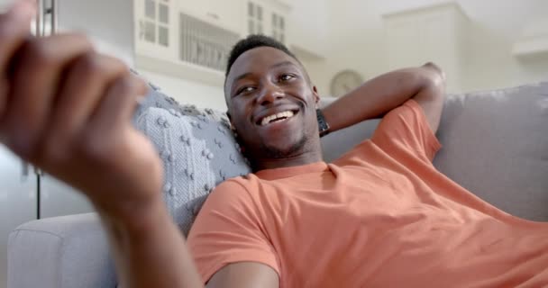 快乐的非洲裔美国人躺在阳光灿烂的客厅里看电视 动作缓慢 Home Domestic Life Lifestyle Wellbeing Communication Technology Unchanged — 图库视频影像
