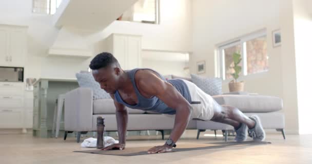 专注的非洲裔美国人在阳光灿烂的客厅里做俯卧撑 动作缓慢 健身和健康的生活方式 — 图库视频影像