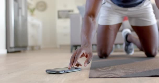 非裔美国人在客厅里用智能手机爬山 动作缓慢 健身和健康的生活方式 — 图库视频影像