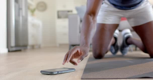 非裔美国人在客厅里用智能手机爬山 动作缓慢 健身和健康的生活方式 — 图库视频影像