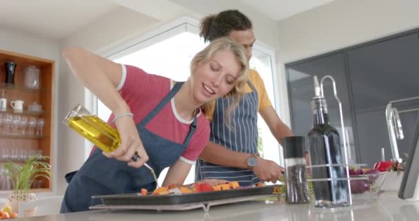 Šťastný Rozmanitý Pár Připravující Čerstvou Zeleninu Olejem Nošení Zástěry Kuchyni — Stock video