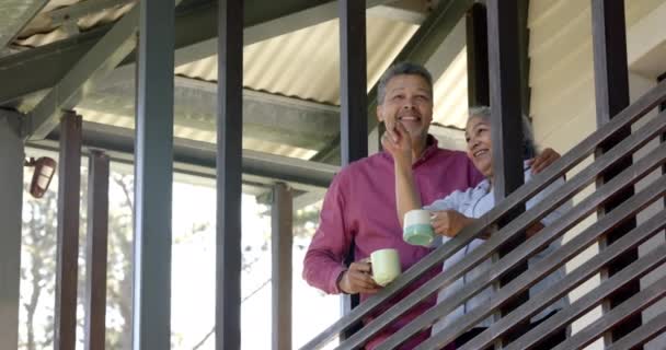 バルコニーに抱擁するハッピーなシニアカップル お茶を飲む レジャー フリータイム トータルネス 国内のライフスタイルコンセプト — ストック動画