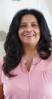 Güneşli odada ayakta durup gülümseyen mutlu son sınıf öğrencisi kadın, ağır çekimde. Emeklilik, refah, ev hayatı ve yaşlı yaşam tarzı, değişmedi..