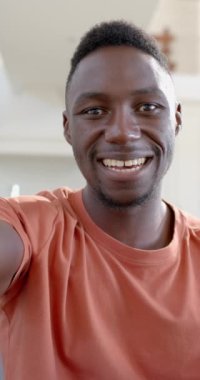 Mutlu Afro-Amerikalı adam güneşli oturma odasında video çekiyor, ağır çekimde. Ev, ev hayatı, yaşam tarzı, refah, iletişim, teknoloji, değişmemiş..