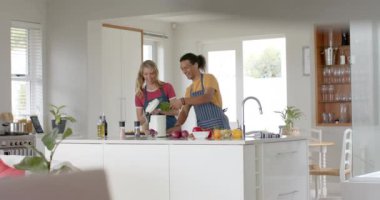 Mutfakta yemek pişiren ve çöpleri atan mutlu çift, yavaş çekim. Sağlıklı, diyet, sağlıklı, diyet, ev hayatı, yemek pişirme, ekoloji ve yaşam tarzı, değişmemiş.