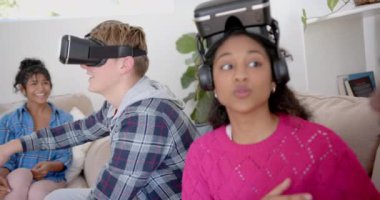 Evde vr kulaklığı kullanan ve konuşan mutlu genç arkadaş grubu, yavaş çekim. Gen Z, arkadaşlık, takılma, teknoloji ve yaşam tarzı, değişmemiş..