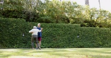 Güneşli bahçede dans eden mutlu son sınıf çifti. Emeklilik, eğlence, boş zaman, birliktelik, dans ve doğa konsepti, değiştirilmemiş..