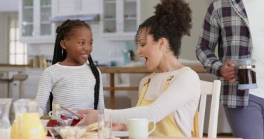 Mutlu Afro-Amerikan ebeveynler ve kızları ağır çekimde kahvaltı yapıyorlar. Aile hayatı, yemek, aile ve yaşam tarzı, değiştirilmemiş..