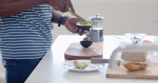 Güneşli Mutfakta Avokado Doğrayan Afrikalı Amerikalı Bir Adam Ağır Çekimde — Stok video