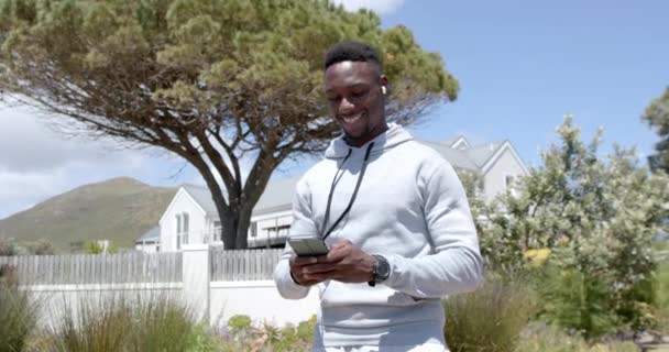 Szczęśliwy Afrykański Amerykanin Jogging Korzystanie Słuchawek Smartfonów Słoneczny Dzień Zwolnione — Wideo stockowe