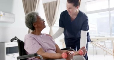 Ağırlıklarla egzersiz yapan çeşitli son sınıf öğrencileri ve hastanede danışmanlık yapan kadın doktorlar, yavaş çekim. İlaç, sağlık ve sağlık hizmetleri, değiştirilmemiş.