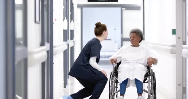 Různorodá Doktorka Mluví Starší Ženou Vozíčku Nemocniční Chodbě Zpomaleně Léky — Stock video