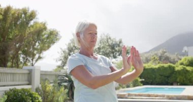 Odaklanmış beyaz kadın, güneşli bahçede yoga yapıyor, yavaş çekim, fotokopi alanı. Arkadaşlar, emeklilik, fitness, refah, ev hayatı ve yaşlılar yaşam tarzı, arkadaşlık, değişmemiş.