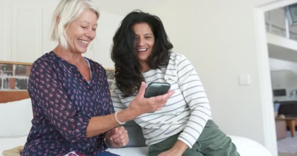 Duas Mulheres Idosas Diversas Felizes Usando Smartphone Rindo Quarto Ensolarado — Vídeo de Stock