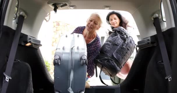 Δύο Χαρούμενες Ηλικιωμένες Γυναίκες Βάζουν Βαλίτσα Και Σακίδιο Στο Αυτοκίνητο — Αρχείο Βίντεο