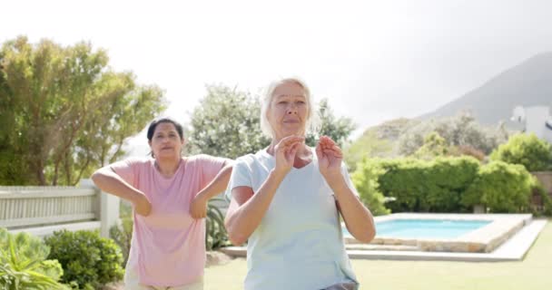 Дві Зосереджені Різноманітні Старші Жінки Практикують Йогу Сонячному Саду Повільний — стокове відео