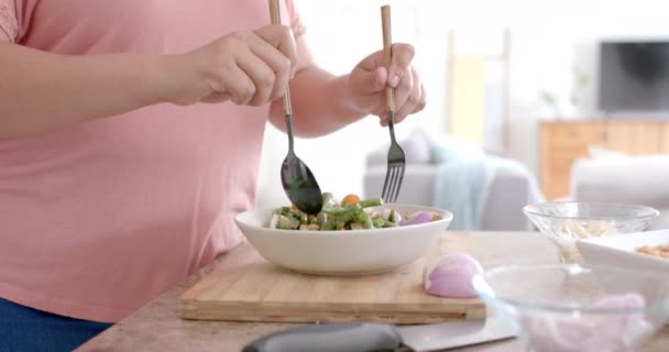 キッチンで野菜サラダのボウルを投げるハッピープラスサイズの女性 スローモーション クッキング 食べ物 家庭生活 健康的なライフスタイル — ストック動画