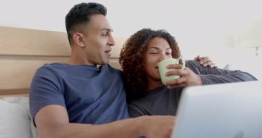 Yatakta, sabah kahve içip laptoplarını yavaş çekimde kullanan mutlu eşcinsel çift. İletişim, boş zaman, gay, ilişki, birliktelik, ev hayatı ve yaşam tarzı, değişmemiş.