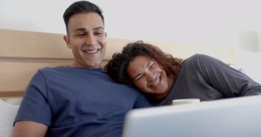 Yatakta, sabah kahve içip laptoplarını yavaş çekimde kullanan mutlu eşcinsel çift. İletişim, boş zaman, gay, ilişki, birliktelik, ev hayatı ve yaşam tarzı, değişmemiş.