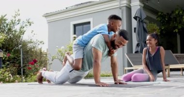 Mutlu Afrika kökenli Amerikalı baba, oğul ve kız bahçede egzersiz yapıyor ve yavaş çekimde oynuyorlar. Aile, birliktelik, eğlence, fitness, egzersiz ve sağlıklı yaşam tarzı, değişmemiş.