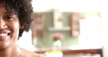 Mutlu Afro-Amerikan kadın portresinin yarısı güneşli oturma odasında gülümsüyor, fotokopi odası, ağır çekim. Yaz, boş zaman, rahatlama, ev hayatı ve yaşam tarzı, değişmemiş..