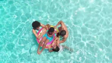 Afrika kökenli Amerikalı ebeveynler, güneşli havuzda şişme havuzda sallanan kız ve erkek çocukları, fotokopi alanı. Yaz, aile, eğlence, birliktelik, tatiller, boş zaman, rahatlama ve yaşam tarzı, değişmemiş.