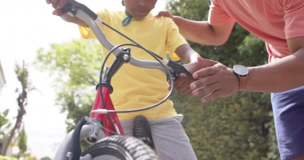Afro Americano Pai Ensinando Filho Andar Bicicleta Jardim Ensolarado Câmera — Vídeo de Stock