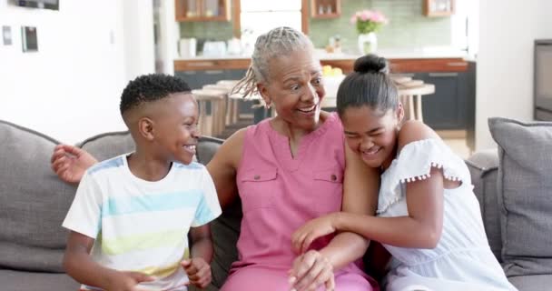ハッピーアフリカ系アメリカ人の孫や祖母がソファーに抱擁し ゆっくりとした動きをしています 子供時代 トータルネス 家庭生活 ライフスタイル 変わらない — ストック動画