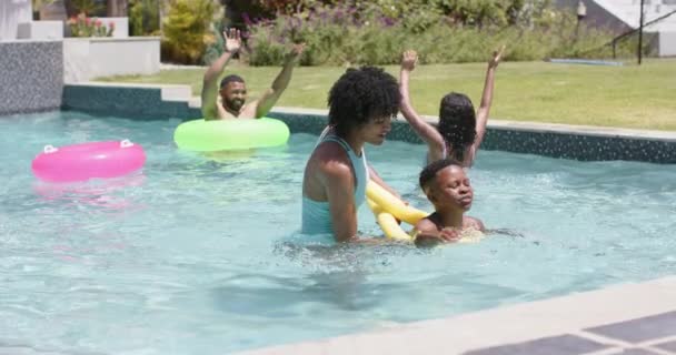 ハッピーアフリカ系アメリカ人の母親は サニープールでヌードルフロートで泳ぐように息子に教えています 楽しみ トータルネス 自由な時間とライフスタイル 変わらない — ストック動画