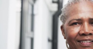 Bahçede gülümseyen, fotokopi çeken ve ağır çekimde gülümseyen yaşlı Afrikalı Amerikalı kadının yarım portresi. Refah ve sağlıklı yaşlı yaşam tarzı, değişmedi..