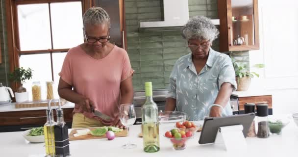 Senior African American Female Friends Cooking Chopping Vegetables Using Tablet — Stock Video