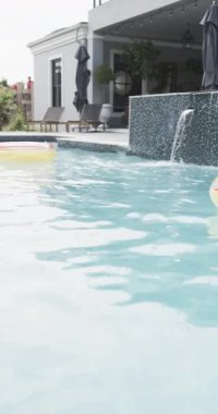 Dikey video son sınıf Afro-Amerikan bayan arkadaşları güneşli havuz kenarında oturuyorlar, fotokopi alanı, ağır çekim. Yaz, tatiller, rahatlama, arkadaşlık, birliktelik ve son sınıf yaşam tarzı, değişmemiş..