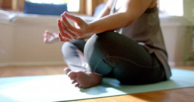 Evde yoga minderi üzerinde meditasyon yapan yaşlı çift ırklı kadın. Ev hayatı, yoga, yaşam tarzı, değişmemiş..