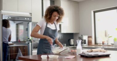 Önlüklü, melez, kek karıştıran, mutfakta pişiren, fotokopi çeken, ağır çekim mutlu bir kadın. Yemek, yemek pişirme, ev hayatı ve yaşam tarzı, değişmemiş..
